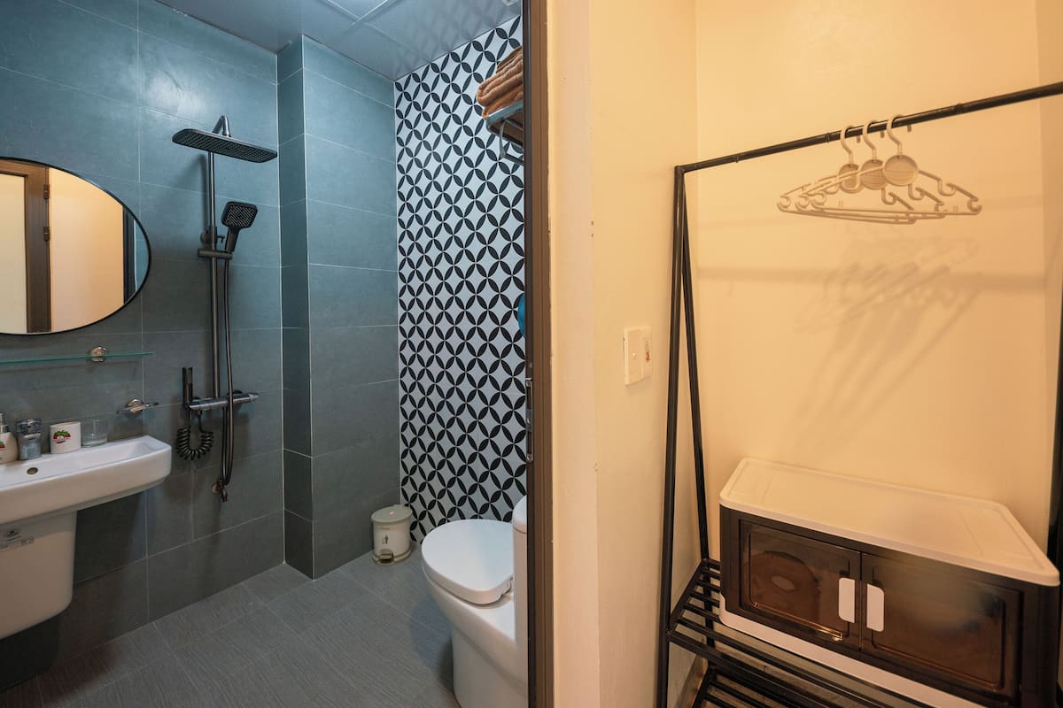 A bathroom with a shower, toilet, sink, and a towel rack.