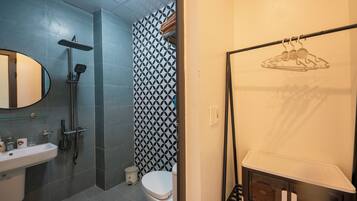 A bathroom with a shower, toilet, sink, and a towel rack.
