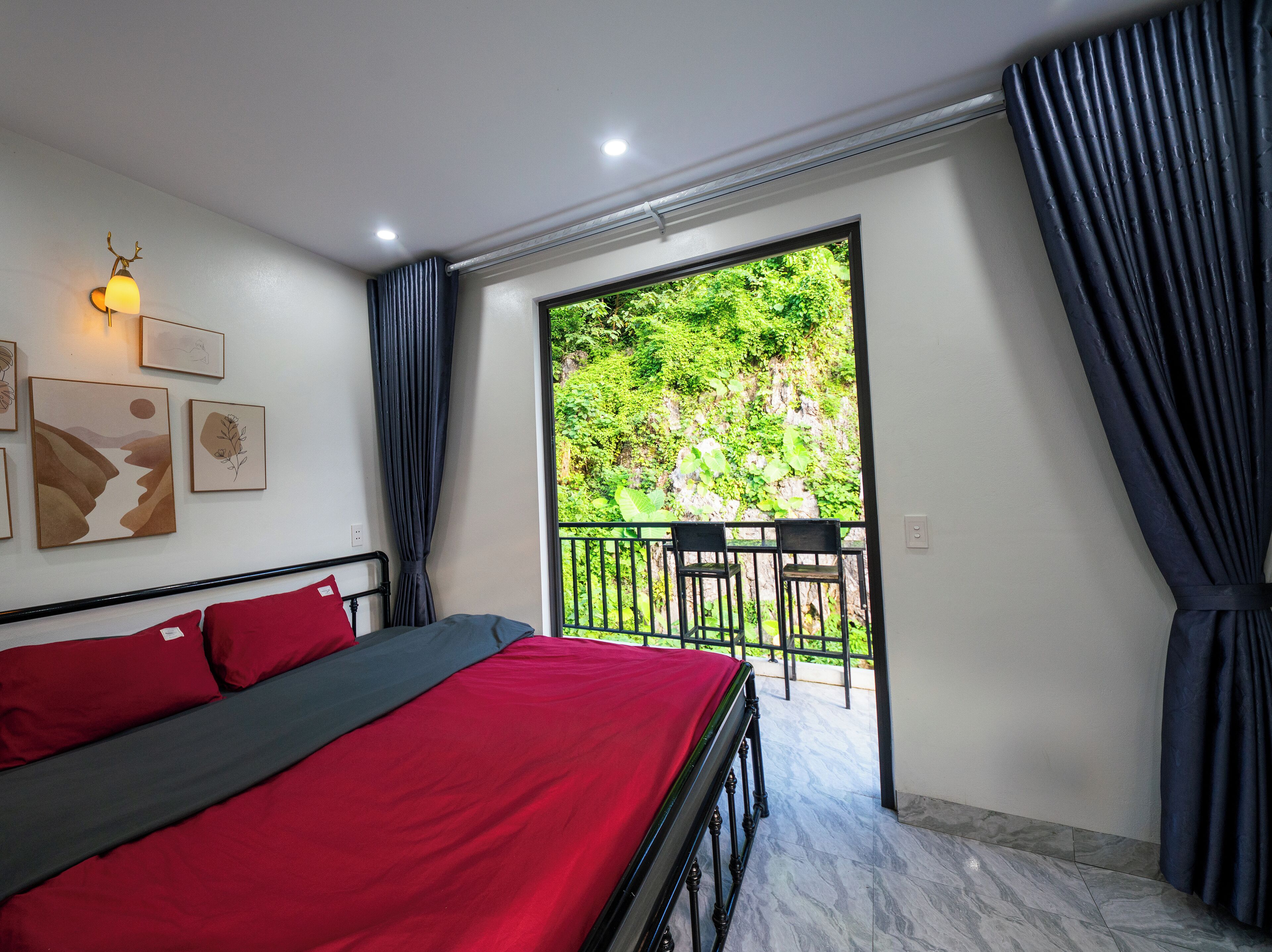 A bedroom with a bed, a balcony with chairs, and artwork on the wall.