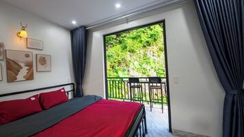 A bedroom with a bed, a balcony with chairs, and artwork on the wall.