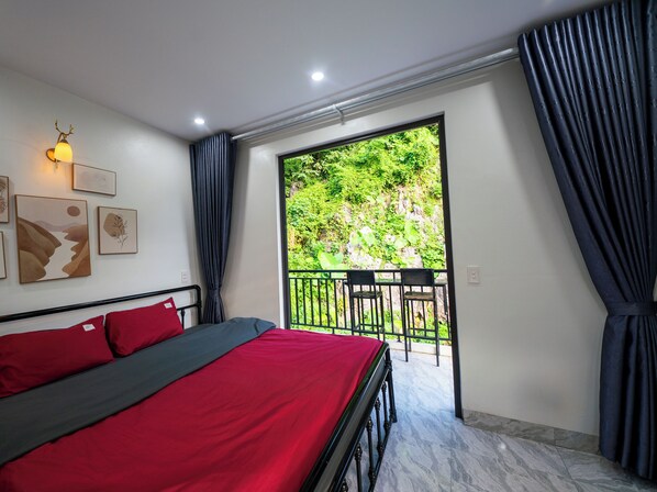 A bedroom with a bed, a balcony with chairs, and artwork on the wall.