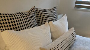 Un lit avec des oreillers à motifs noirs et blancs, un oreiller blanc texturé et un oreiller blanc à pois noirs.