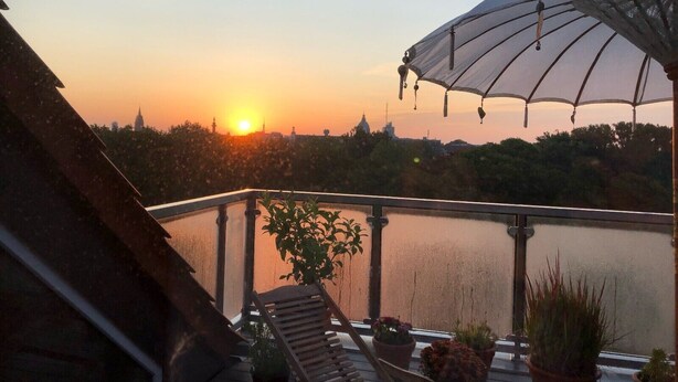 A sunset view from a balcony with a water body, lounge chairs, and potted plants. - Apartment 'Ruhe Über Den Dächern Hannovers' with Private Terrace, Balcony and Wi-Fi (Hannover)
