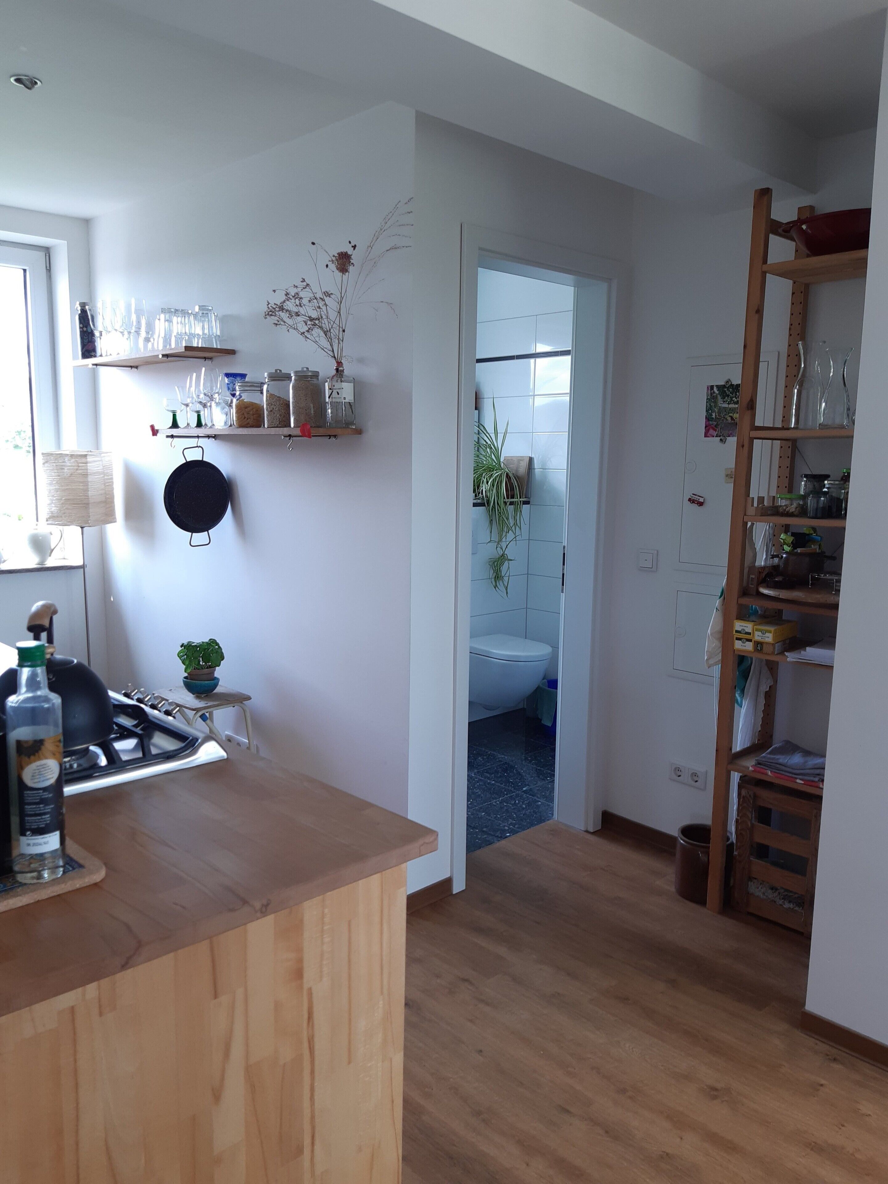 Una cocina con encimera de madera, estufa y repisas con frascos y botellas de vidrio.