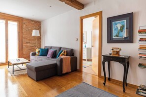 A modern living room with a sectional sofa, a wooden coffee table, a lamp, a framed picture, and a bookshelf. - Apartamento junto al Ayuntamiento - by wehomes (Santander)