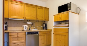 A kitchen with wooden cabinets, a dishwasher, a microwave, and a coffee maker.