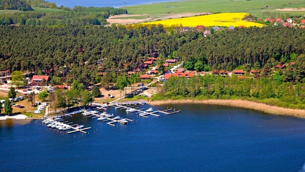 An aerial view of a lakeside village with a marina, surrounded by forested areas and fields. - Holiday Apartment 'Maribell' with Lake View, Balcony and Wi-Fi (Jabel)