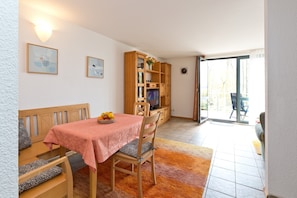 A dining area with a table, chairs, a bench, a television, and a bookshelf. - Holiday Apartment 'Maribell' with Lake View, Balcony and Wi-Fi (Jabel)