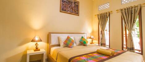 A hotel room with a large bed, two bedside tables with lamps, a colorful quilt, and a framed picture on the wall.