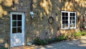 Un bâtiment en briques avec une porte et une fenêtre blanches, un petit porche et une lanterne.