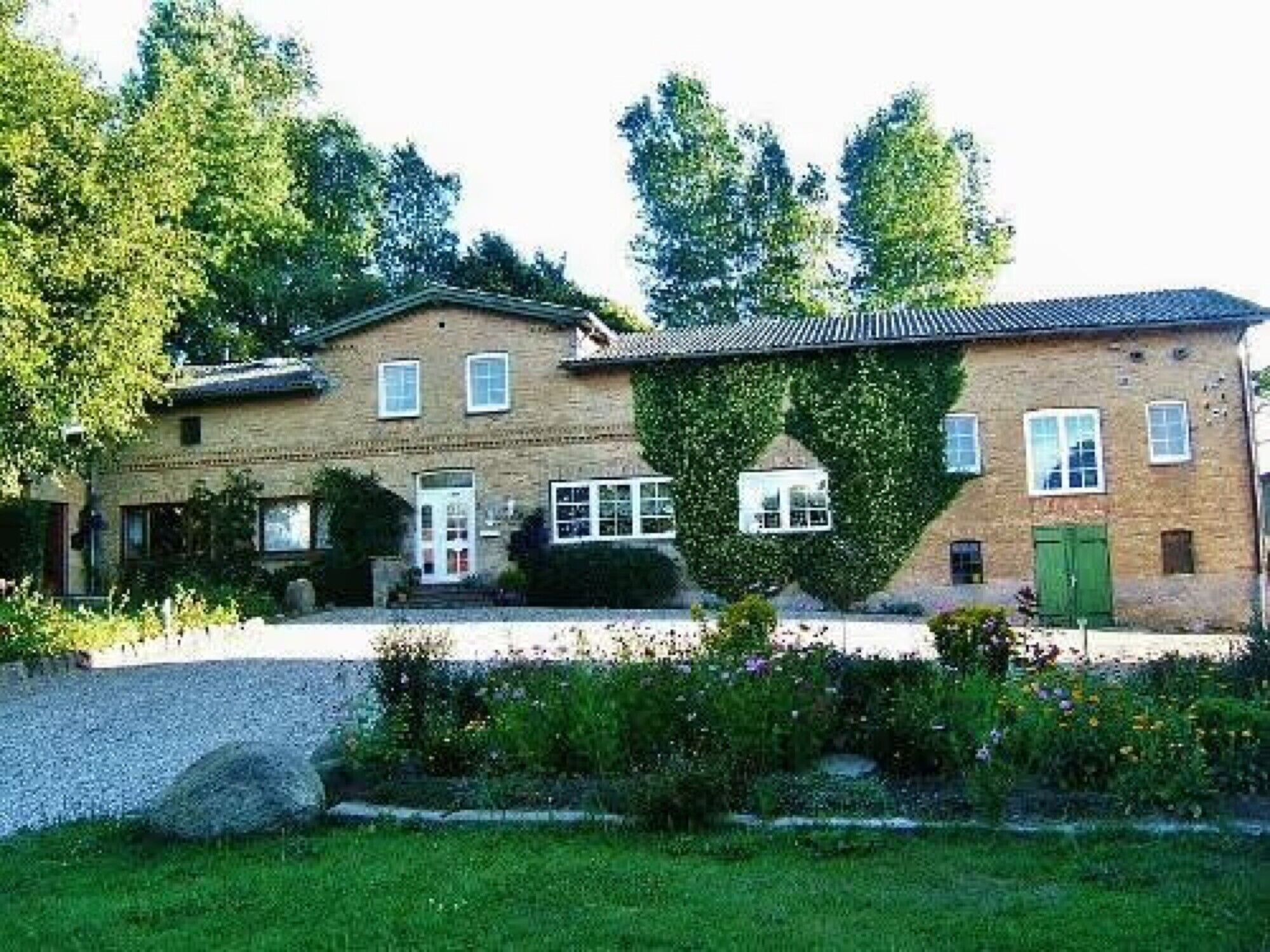 Una casa a due piani con facciata in mattoni, una porta verde e un piccolo portico.