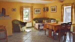 Un coin repas avec une table et des chaises en bois, un canapé et une fenêtre avec des rideaux.