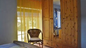 Une pièce comprenant un lit, une chaise et une armoire en bois avec un miroir.
