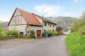 Ein zweistöckiges Haus mit geneigtem Dach, einer sichtbaren Garagentür und einem gepflasterten Einfahrt.
