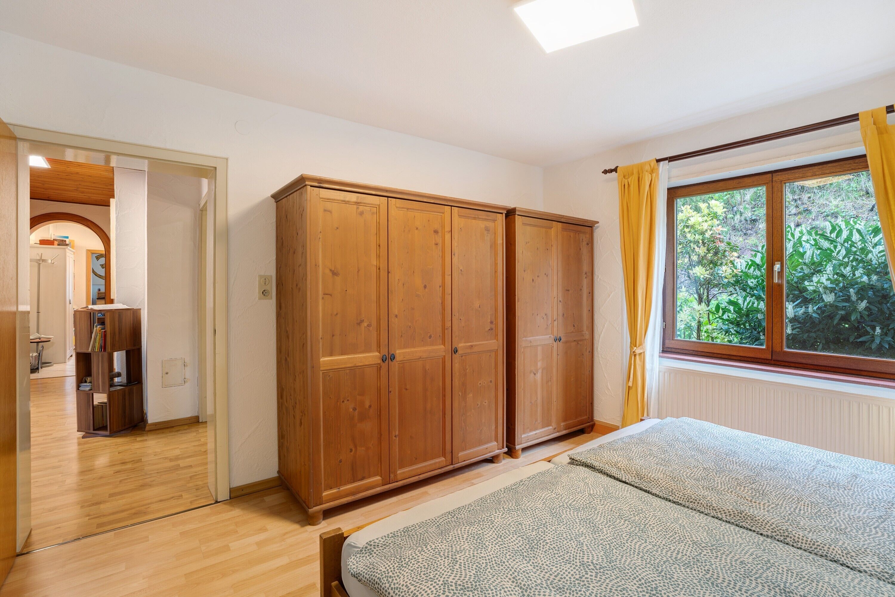 Une chambre à coucher avec un lit, une armoire en bois et une fenêtre avec des rideaux.