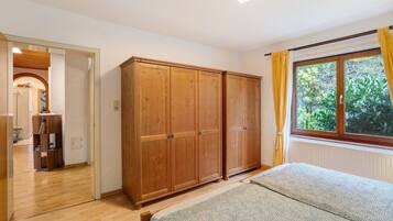 Une chambre à coucher avec un lit, une armoire en bois et une fenêtre avec des rideaux.