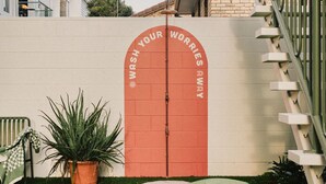 A red door with the text "WASH YOUR WORRIES AWAY" on a white wall.
