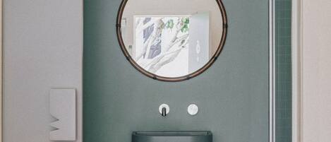 A bathroom with a round mirror, a sink, and a light switch.