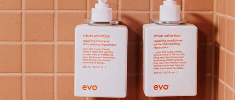 Deux flacons de shampoing et d’après-shampoing « ritual salvation » de la marque « evo », placés contre un mur carrelé.