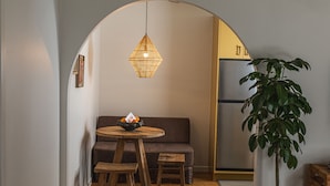 A cozy dining area with a wooden table and chairs, a hanging light fixture, and a plant.