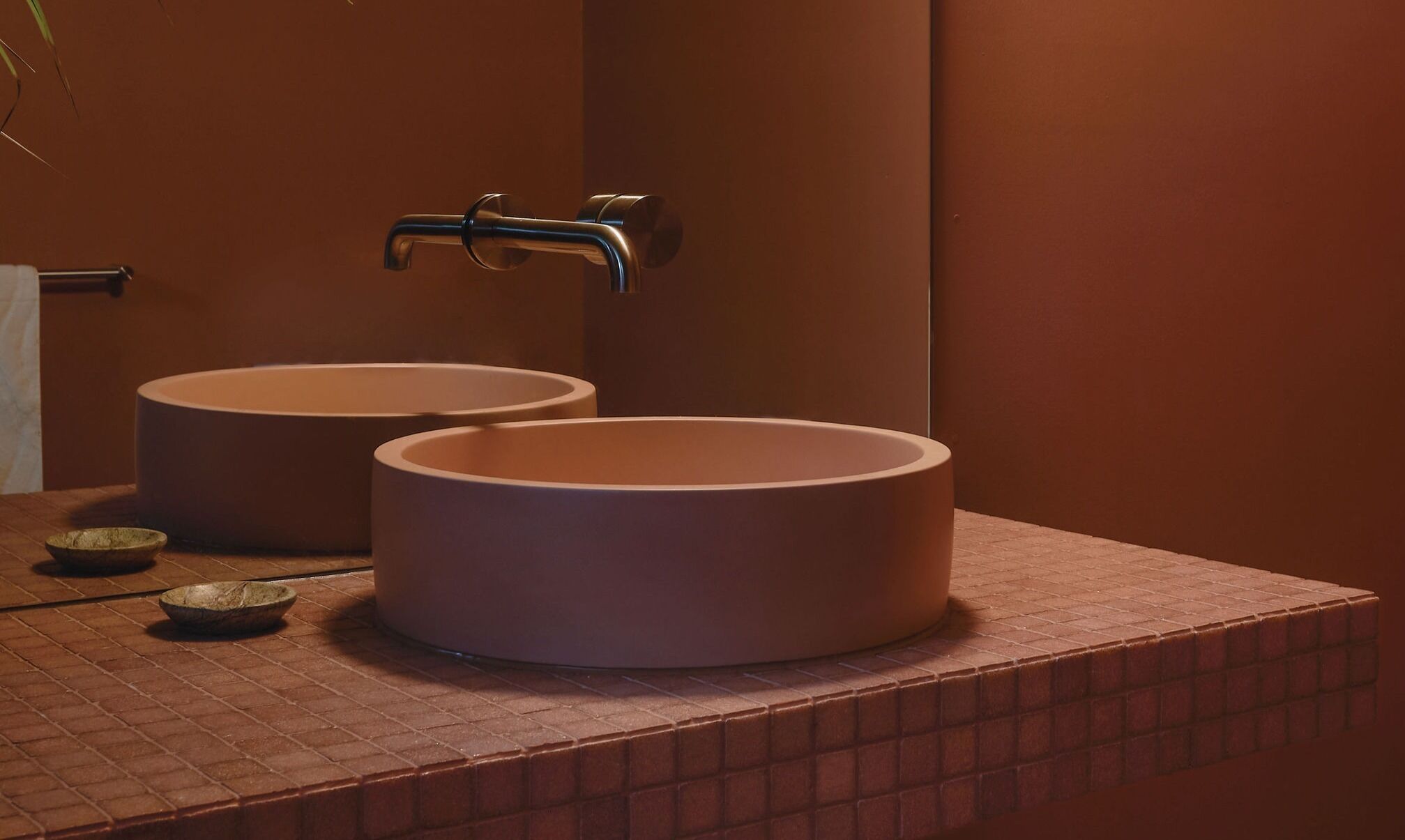A bathroom with two round sinks and a towel rack.