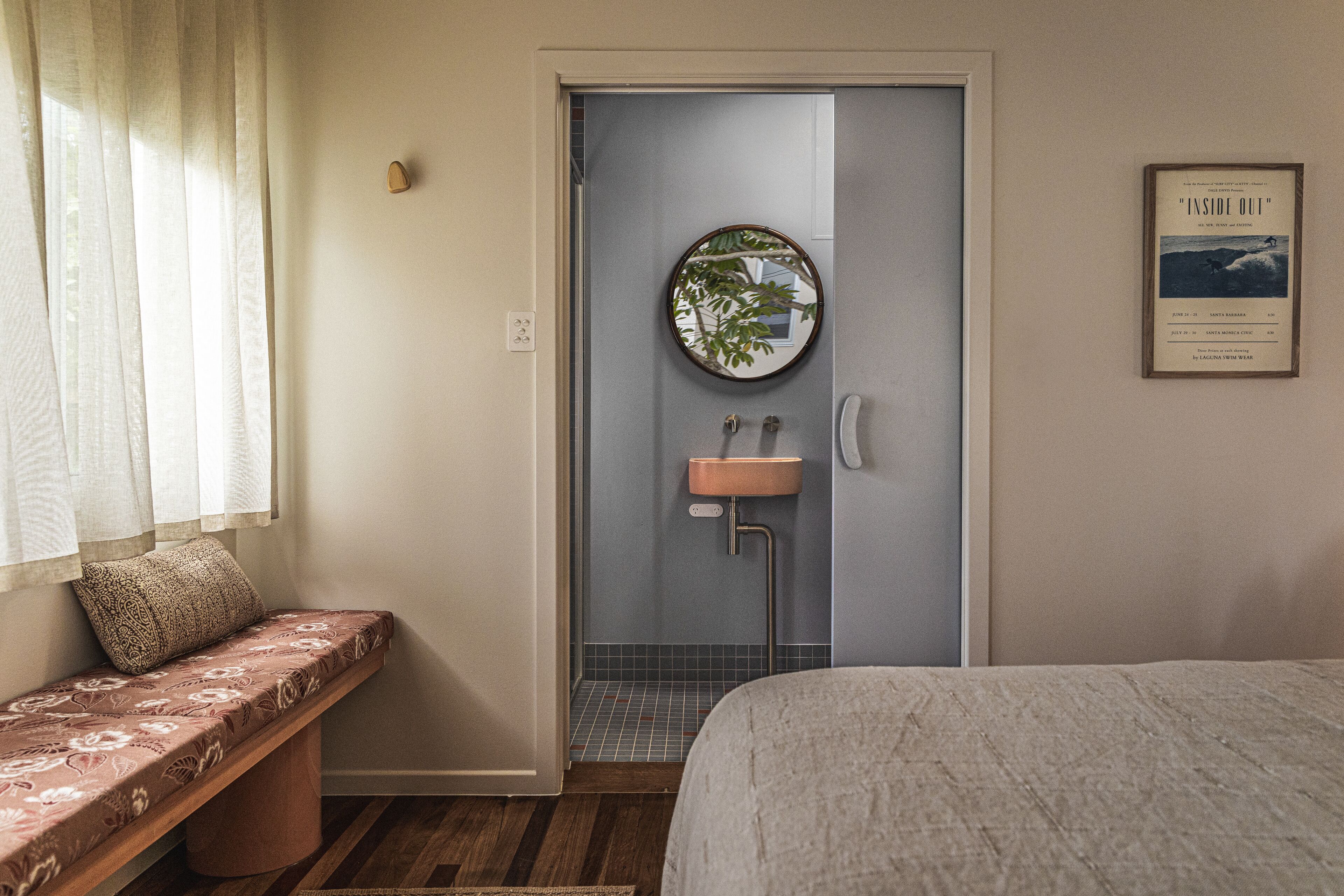 A bathroom with a bench, a sink, and a mirror.