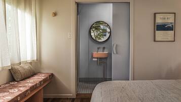 A bathroom with a bench, a sink, and a mirror.