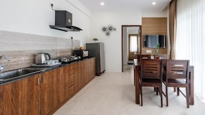 Een moderne keuken met houten kastjes, een zwarte afzuigkap en een ingebouwde magnetron. Er is een eethoek met een houten tafel en stoelen.