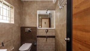 Een badkamer met toilet, wastafel, spiegel en douche.