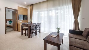 Een moderne woonkamer met een eethoek, een bank, een salontafel en een aan de muur bevestigde televisie.