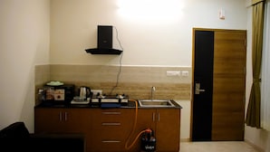 Een compacte keuken met een gasfornuis, magnetron en een klein spoelbakje. Er is een kast met lades en een deur die naar een andere kamer leidt.