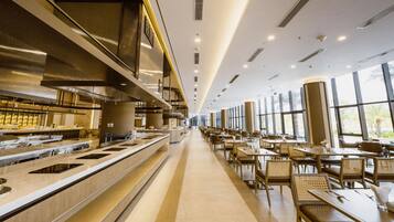 Un restaurante moderno con una barra larga, varias mesas y ventanas amplias que dejan entrar luz natural.