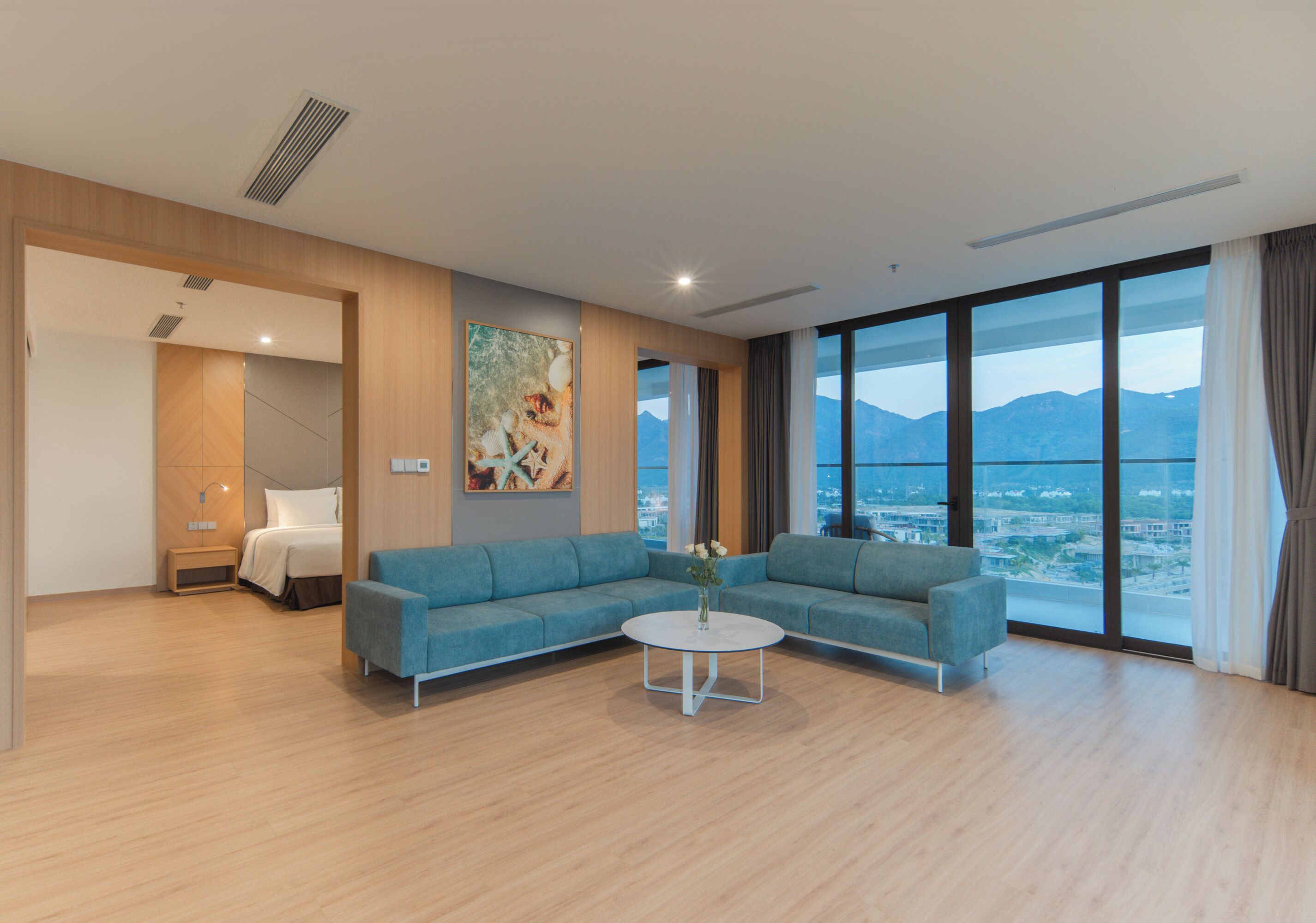 Una habitación de hotel moderna con un sofá grande, una mesita redonda y un cuadro en la pared.