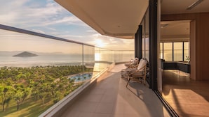 Un balcon avec vue sur une plage et une piscine, aménagé avec des chaises et une table.
