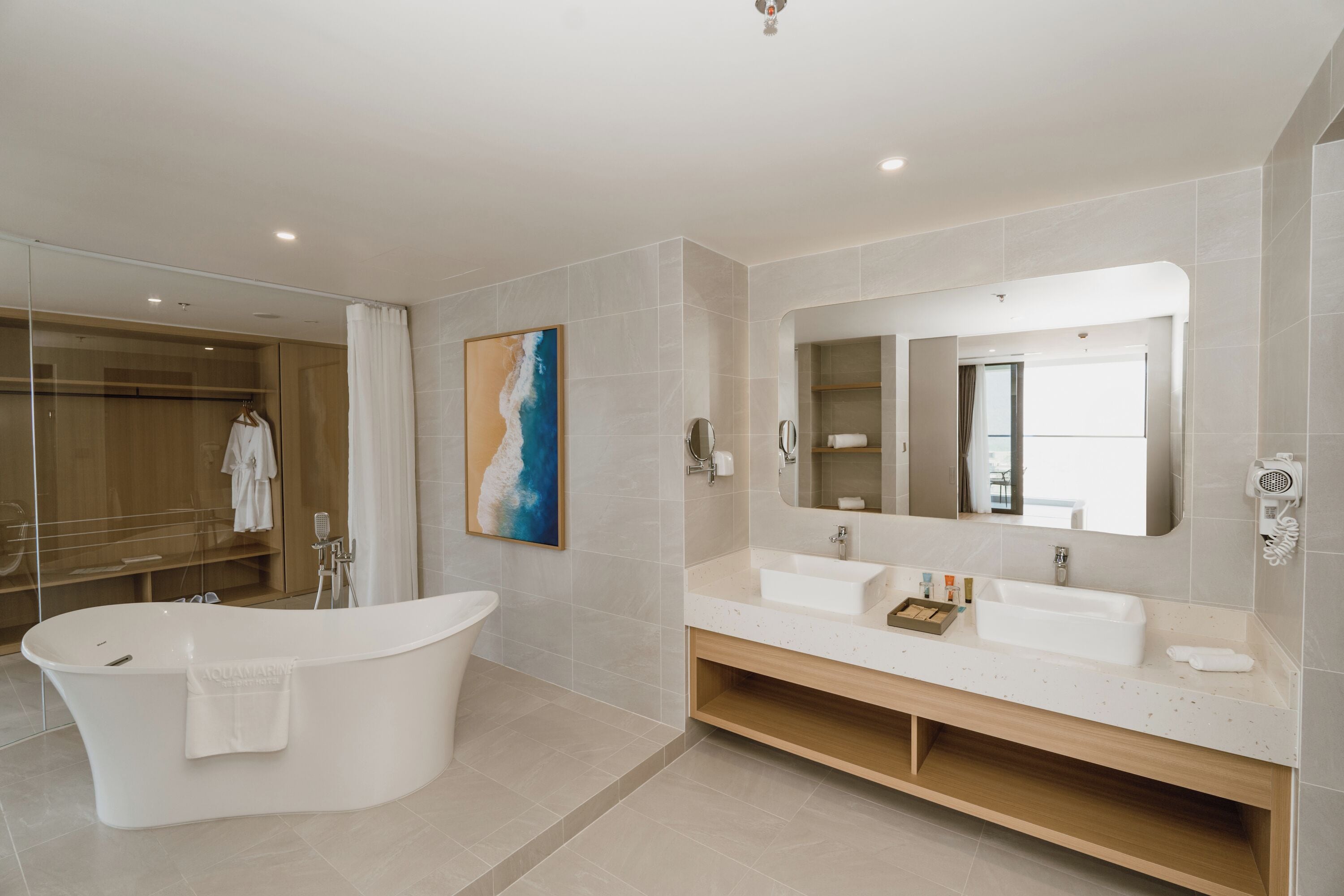 A modern bathroom with a freestanding bathtub, a large mirror, and a vanity with two sinks.