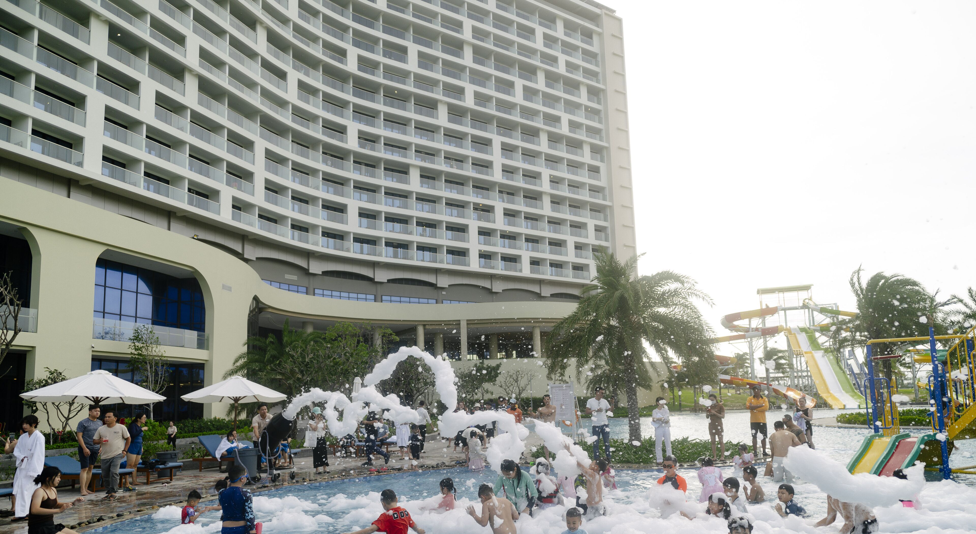 Um hotel com uma grande área de piscina, toboáguas e uma palmeira.