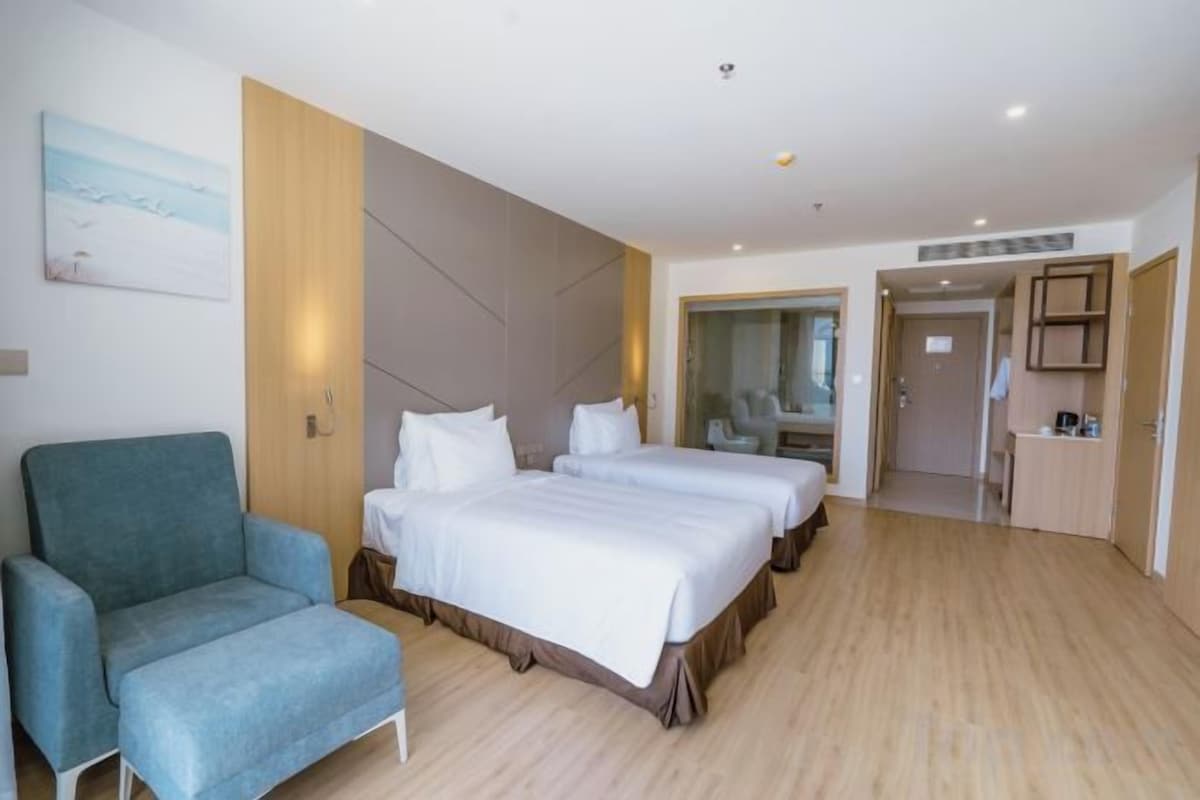 A hotel room with a bed, a chair, a desk, and a mirror.