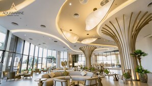 Un hall d’entrée spacieux au design moderne, doté d’un grand espace salon, d’un plafond incurvé avec un éclairage original et de grandes fenêtres laissant entrer la lumière naturelle.