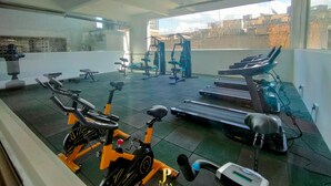 Un gimnasio con equipo de ejercicio, incluyendo una bicicleta estática, cinta de correr y máquinas de pesas.