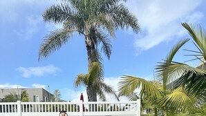 A parking area with a white fence, a visitor parking sign, and a green EV parking sign. - Coastal Haven Unbeatable Beach and Village Location  (Carlsbad)