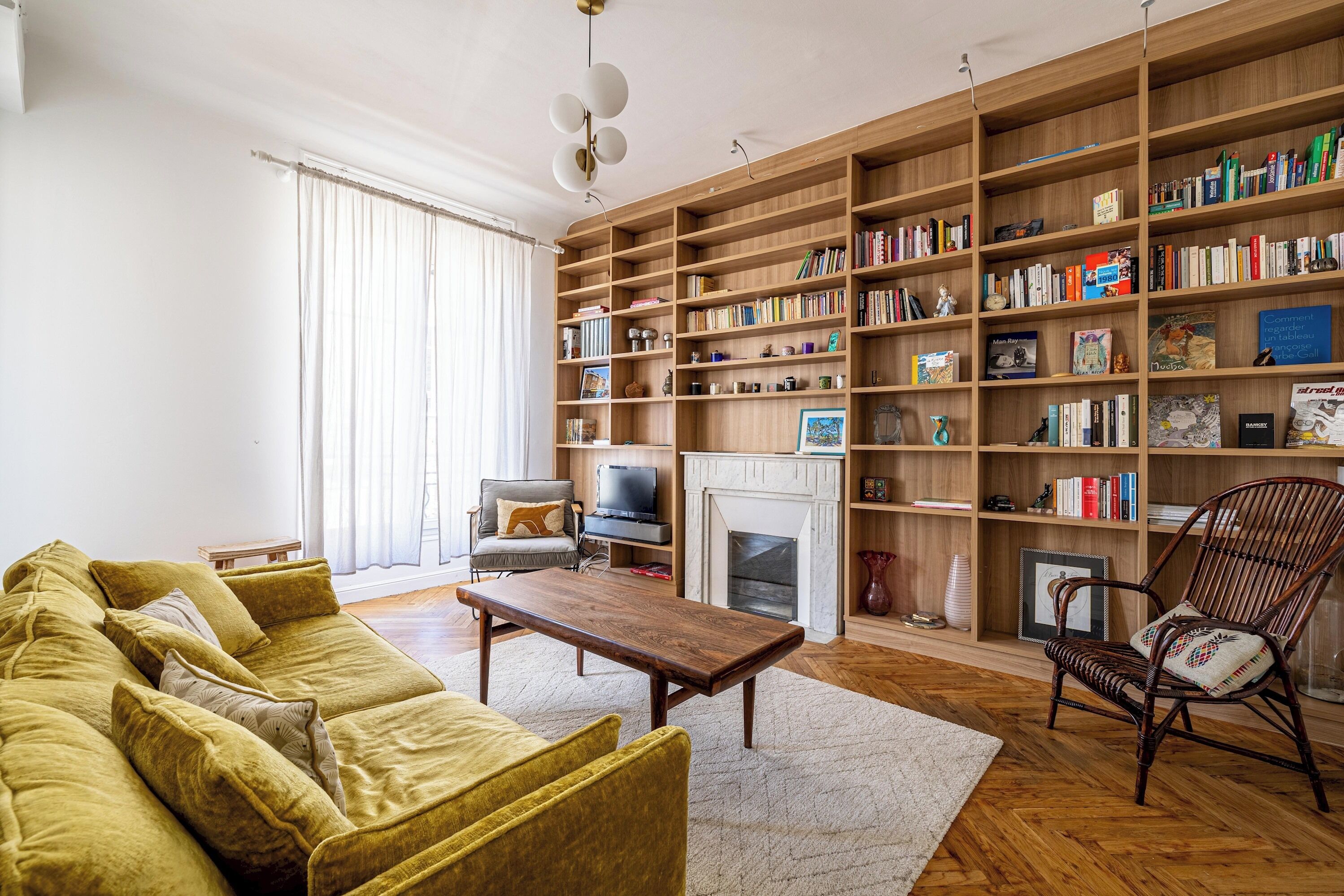 A living room with a sofa, a wooden coffee table, a bookshelf, a fireplace, and a television.