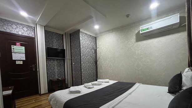 A hotel room with a bed, a desk, a wardrobe, and an air conditioning unit. - Sun Hotel Hostel (Tashkent)