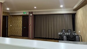 A conference room with a long table and chairs, a curtain, and an exit sign. - Sun Hotel Hostel (Tashkent)