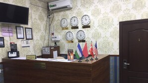 A reception desk with clocks, flags, and a sign indicating check-out time. - Sun Hotel Hostel (Tashkent)