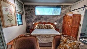 A bedroom with a bed, two chairs, a nightstand, a wardrobe, and a window. - Maison Dandelion (Franschhoek)