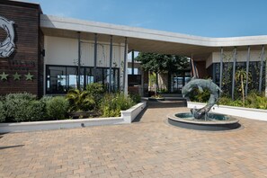 A modern building with a curved roof, a fountain, and a landscaped garden area. - Ballito Hills Unit 79 (Ballito)