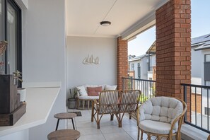A balcony with wicker chairs, a small table, and a sofa with cushions. - Ballito Hills Unit 79 (Ballito)