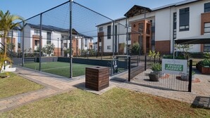 A residential area with a fenced sports court, a brick pathway, and a sign for a Veggie Garden. - Ballito Hills Unit 79 (Ballito)