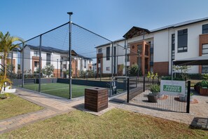 A residential area with a fenced sports court, a brick pathway, and a sign for a Veggie Garden. - Ballito Hills Unit 79 (Ballito)