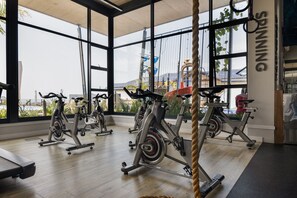 A gym with stationary bikes, large windows, and a view of a water park. - Ballito Hills Unit 79 (Ballito)